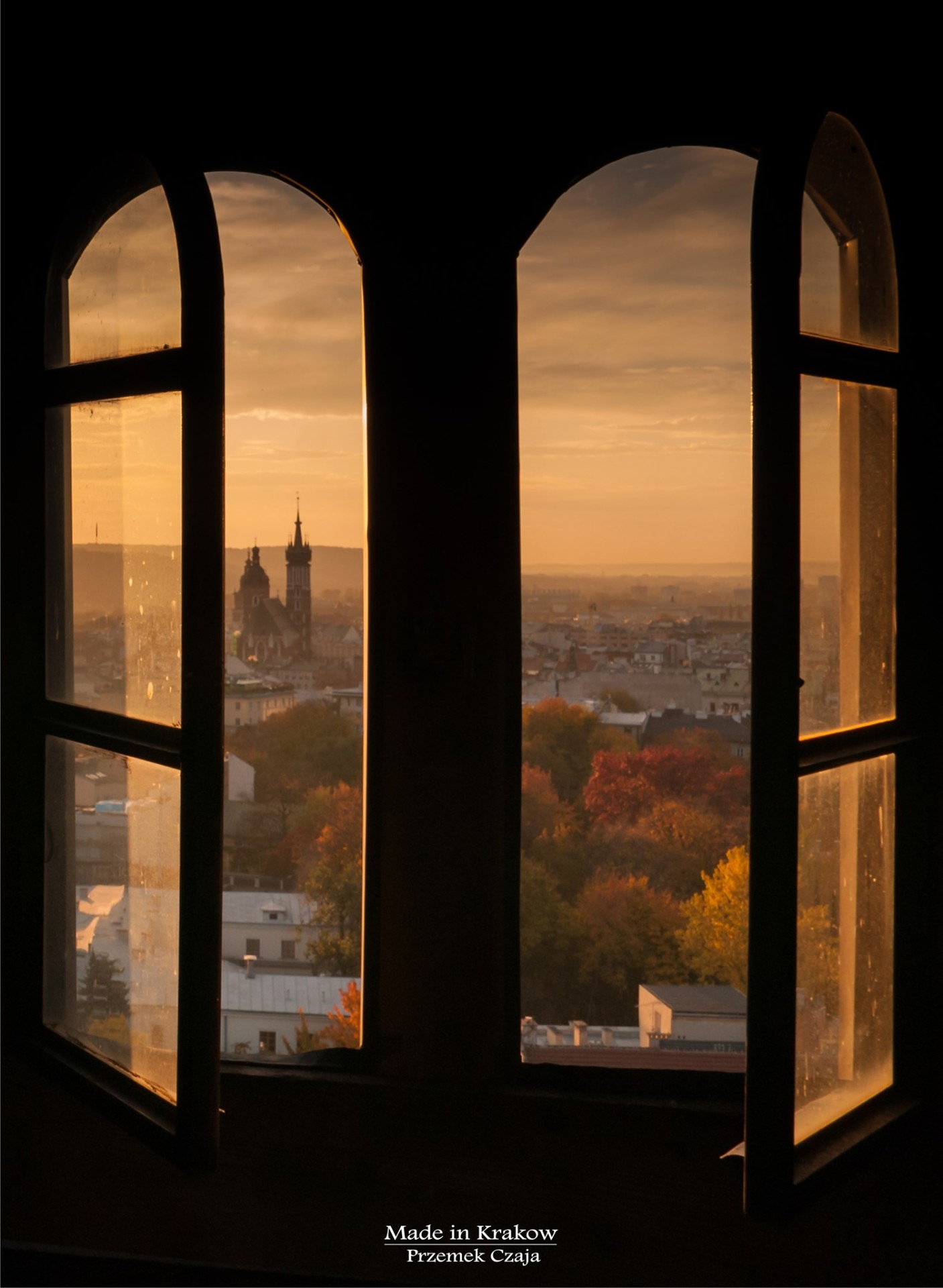 View of Kraków's Old Town and St. Mary's spire through an arched window at sunset
